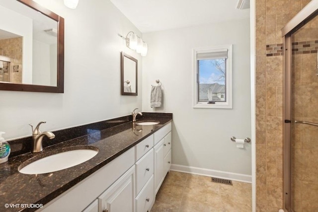 full bath with tiled shower, a sink, visible vents, and baseboards