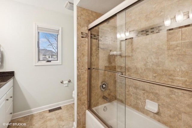 bathroom featuring bath / shower combo with glass door, visible vents, vanity, baseboards, and tile patterned floors