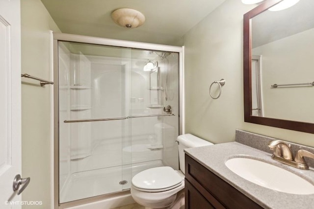 bathroom featuring toilet, a shower stall, and vanity