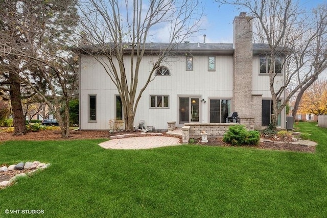 back of property with a chimney, central AC, a lawn, and a patio