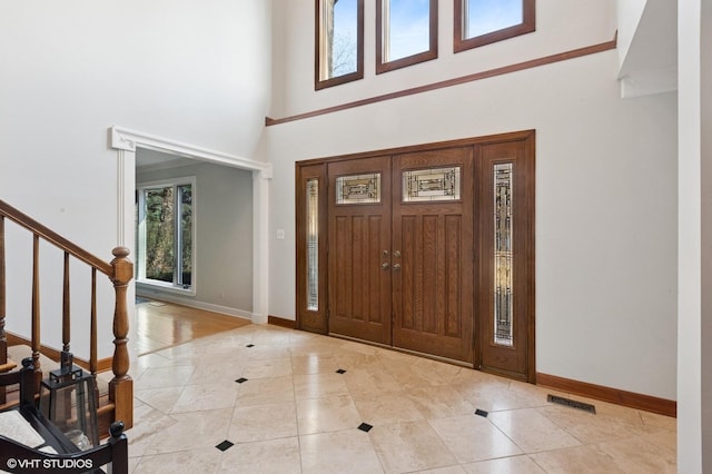 foyer entrance featuring stairs, plenty of natural light, visible vents, and baseboards