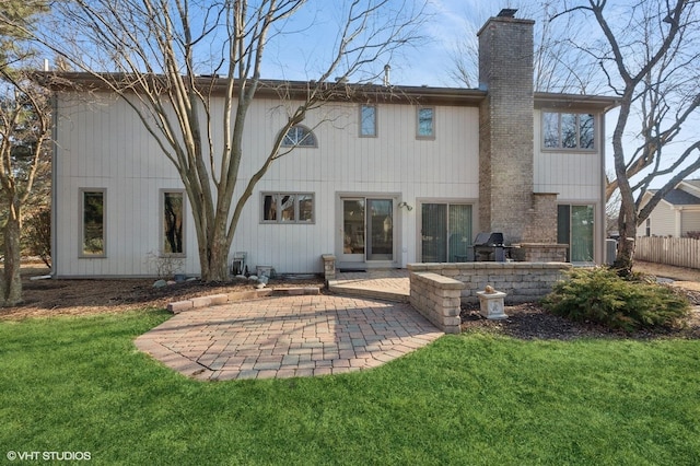 rear view of property with a patio area, a lawn, a chimney, and fence