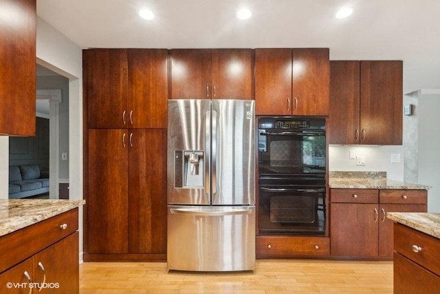 kitchen with light wood-style flooring, recessed lighting, dobule oven black, light stone countertops, and stainless steel fridge