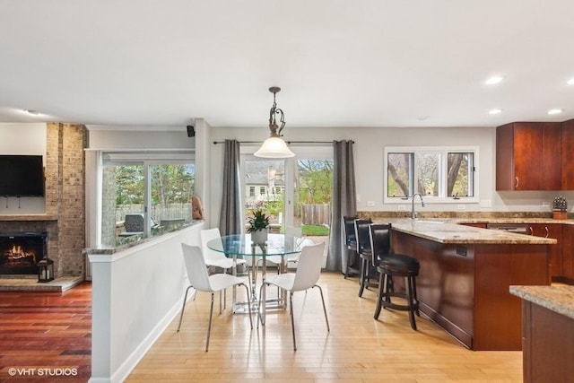 dining space featuring plenty of natural light, light wood finished floors, and a brick fireplace