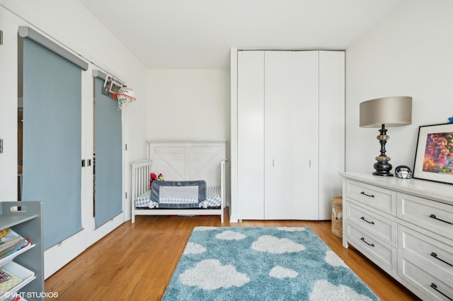 bedroom with a closet, light hardwood / wood-style floors, and a crib