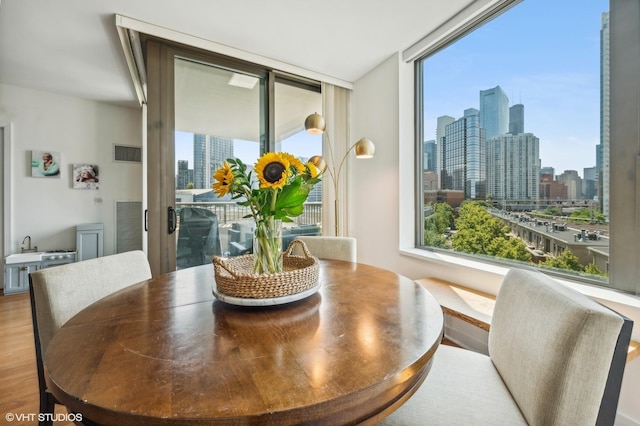 dining room with plenty of natural light, floor to ceiling windows, and light hardwood / wood-style floors