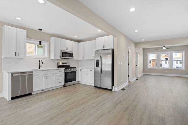 kitchen featuring white cabinetry, ceiling fan, sink, hanging light fixtures, and stainless steel appliances