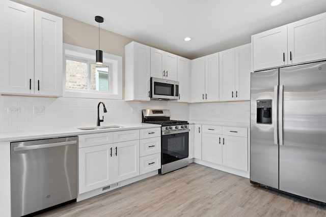 kitchen featuring appliances with stainless steel finishes, white cabinetry, pendant lighting, and sink