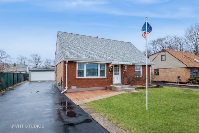 bungalow-style home with a garage, an outdoor structure, and a front yard