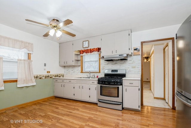 kitchen featuring sink, tasteful backsplash, appliances with stainless steel finishes, white cabinets, and light wood-type flooring