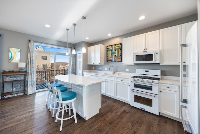 kitchen featuring white cabinetry, decorative light fixtures, white appliances, and a center island