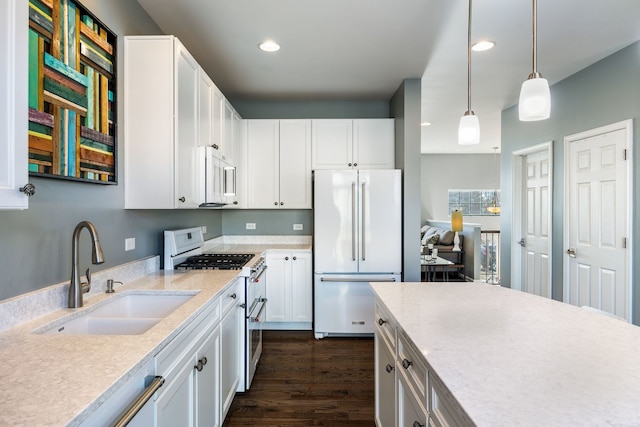 kitchen featuring sink, white appliances, white cabinets, and hanging light fixtures