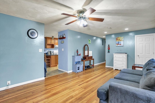 living room featuring a textured ceiling, light wood-type flooring, and ceiling fan