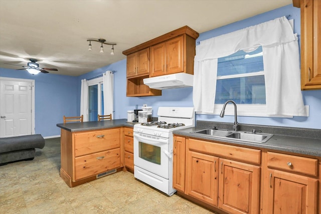 kitchen with kitchen peninsula, white gas range oven, ceiling fan, and sink