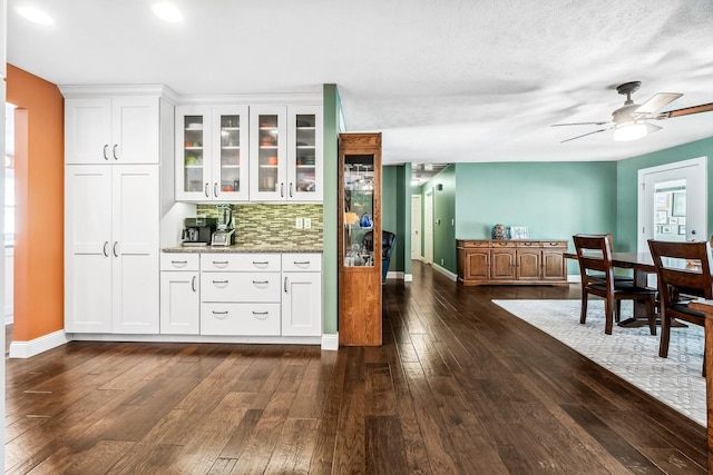 bar featuring white cabinets, dark hardwood / wood-style flooring, backsplash, and light stone countertops