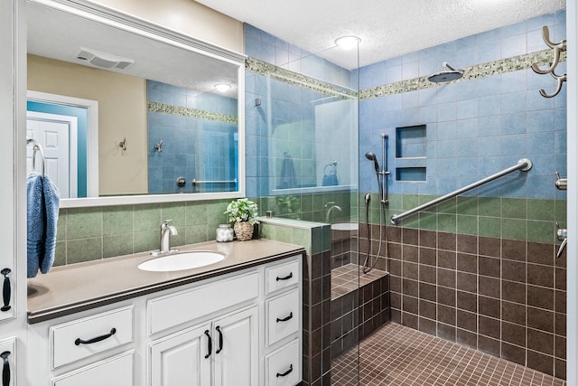 bathroom with a textured ceiling, a tile shower, backsplash, and vanity