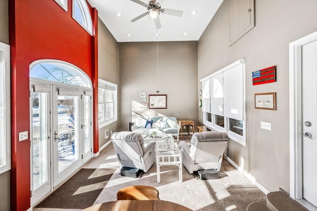 sitting room with a high ceiling, ceiling fan, french doors, and light carpet