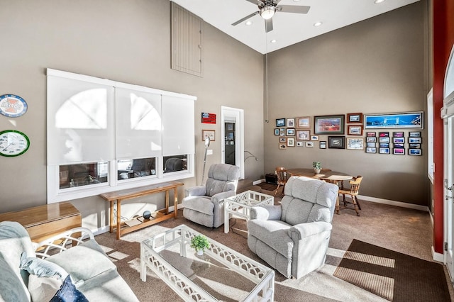 living room featuring a towering ceiling, ceiling fan, and carpet flooring