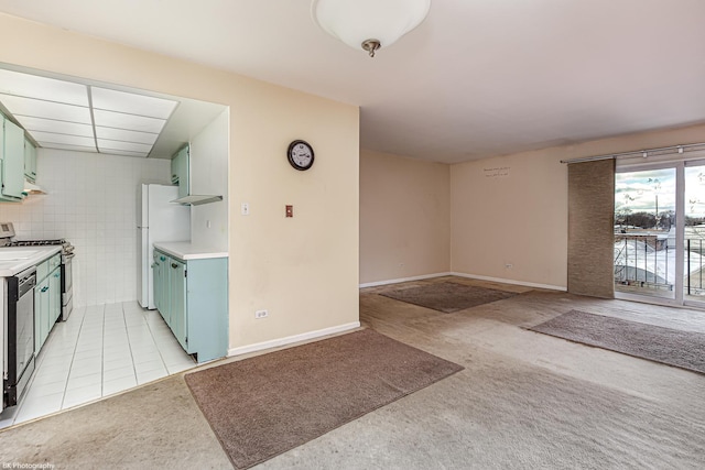 kitchen featuring white refrigerator, green cabinets, light carpet, and stainless steel range