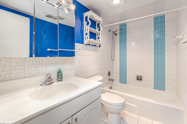 full bathroom featuring vanity, tiled shower / bath, tile patterned flooring, toilet, and tile walls