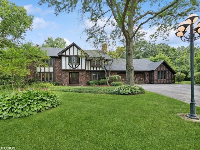 tudor home featuring a garage and a front lawn