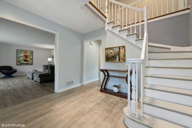 stairway featuring wood-type flooring and a textured ceiling