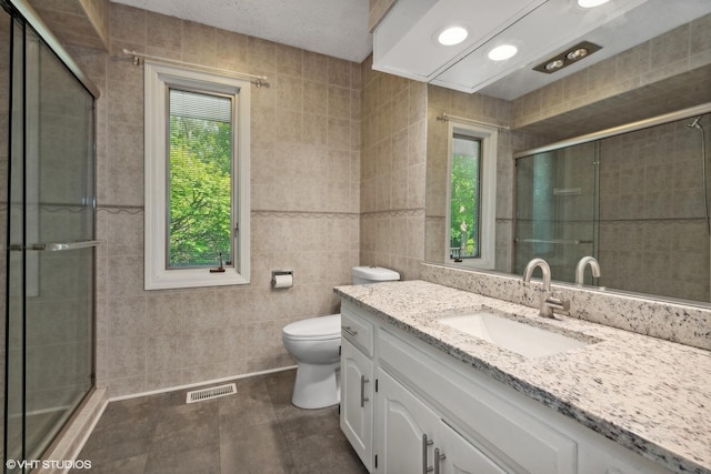 bathroom featuring vanity, a healthy amount of sunlight, tile walls, and toilet