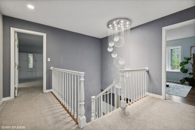 hallway with a notable chandelier and carpet flooring