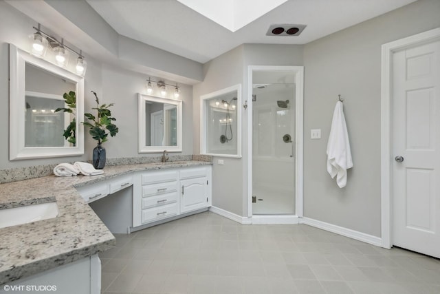 bathroom with a skylight, vanity, and a shower with shower door