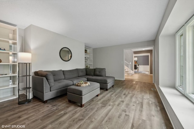 living room featuring hardwood / wood-style flooring, built in features, and a textured ceiling