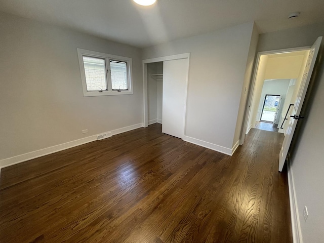 unfurnished bedroom featuring a closet and dark wood-type flooring