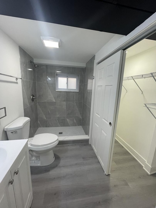 bathroom featuring vanity, toilet, wood-type flooring, and a tile shower