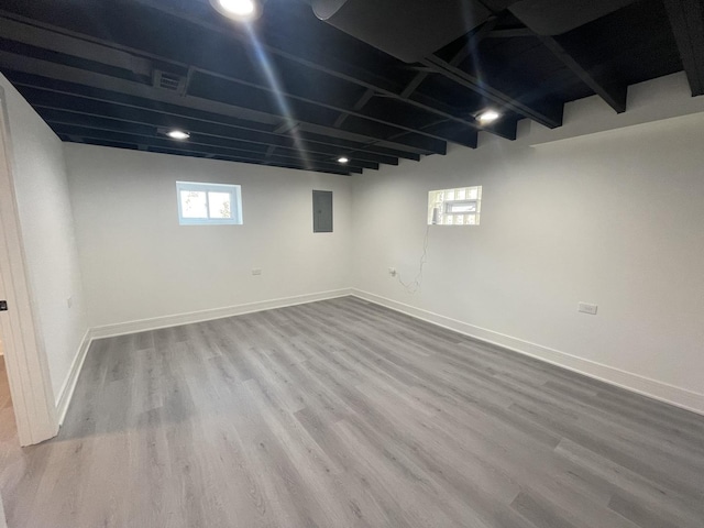 basement featuring electric panel and hardwood / wood-style flooring