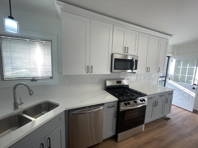 kitchen with appliances with stainless steel finishes, decorative light fixtures, white cabinetry, and sink