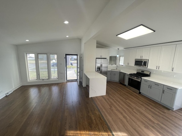 kitchen with sink, hanging light fixtures, dark wood-type flooring, vaulted ceiling, and appliances with stainless steel finishes