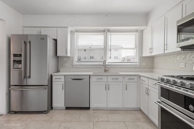 kitchen featuring decorative backsplash, stainless steel appliances, white cabinetry, and sink