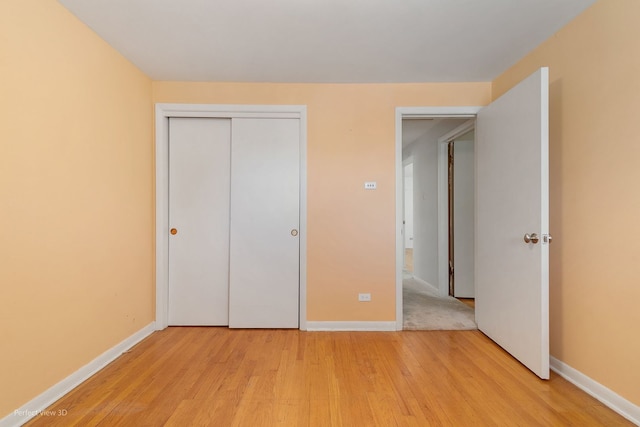 unfurnished bedroom with light wood-type flooring and a closet