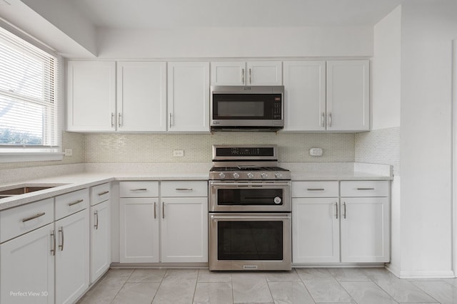 kitchen featuring white cabinets, sink, backsplash, and appliances with stainless steel finishes