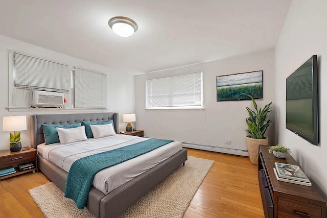 bedroom featuring cooling unit, baseboard heating, and light hardwood / wood-style flooring