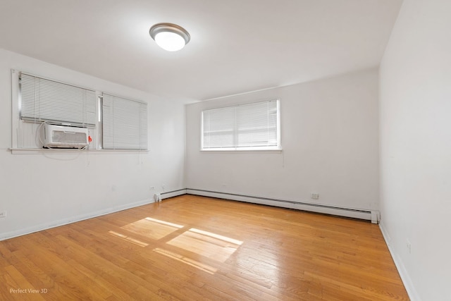 spare room featuring light hardwood / wood-style floors, baseboard heating, and cooling unit