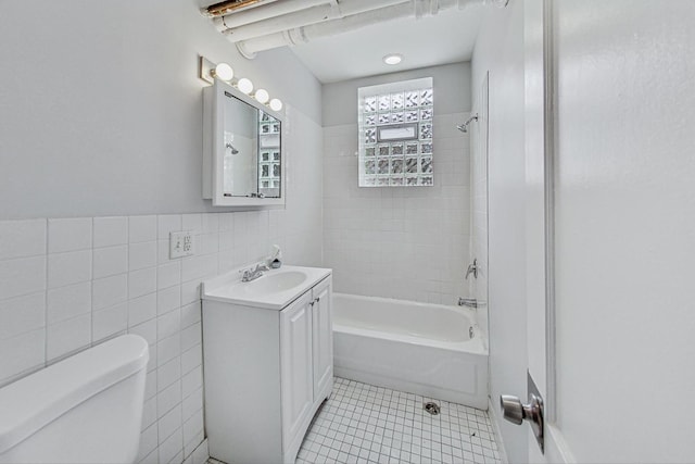 full bathroom with vanity, tiled shower / bath, tile patterned flooring, toilet, and tile walls