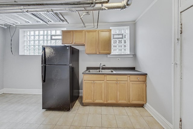 kitchen with light tile patterned floors, black fridge, crown molding, and sink