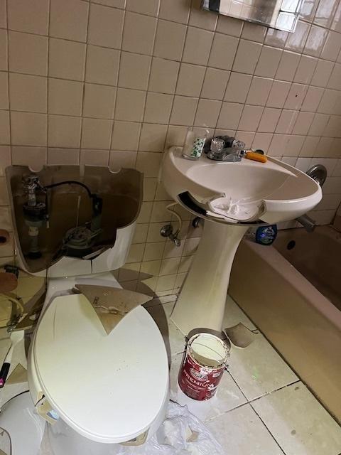 bathroom with tile patterned floors, tile walls, and a tub