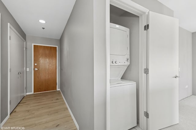 clothes washing area featuring stacked washer / drying machine and light wood-type flooring