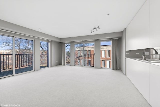 living room featuring track lighting, light colored carpet, and sink