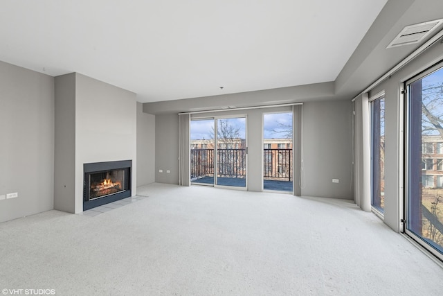 unfurnished living room featuring light colored carpet and plenty of natural light