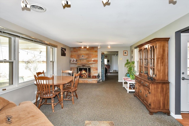 carpeted dining area with rail lighting and a fireplace