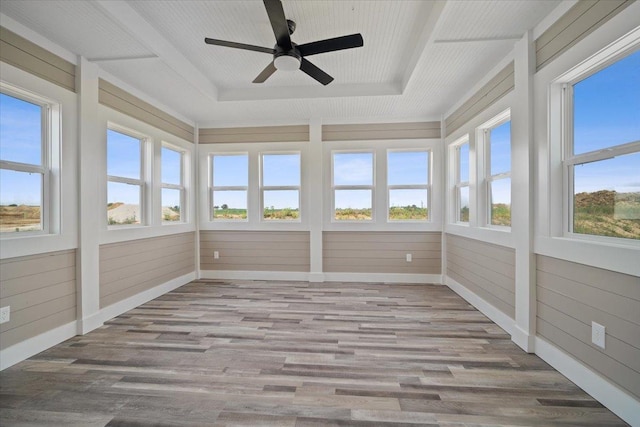 unfurnished sunroom with ceiling fan and a tray ceiling