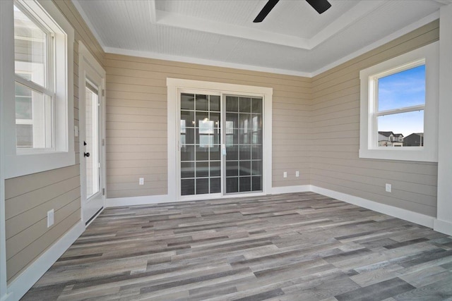 unfurnished sunroom with ceiling fan and a tray ceiling