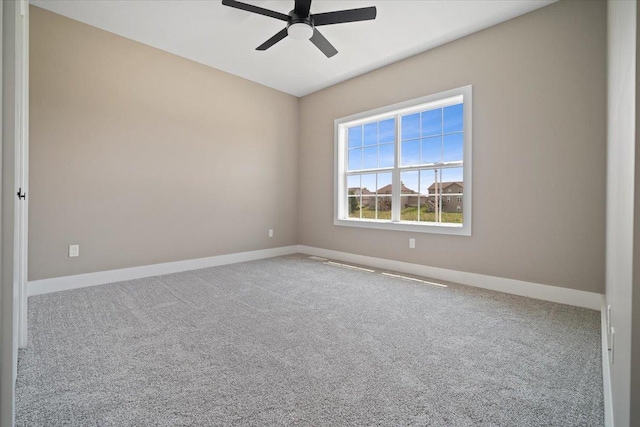 carpeted empty room with a ceiling fan and baseboards